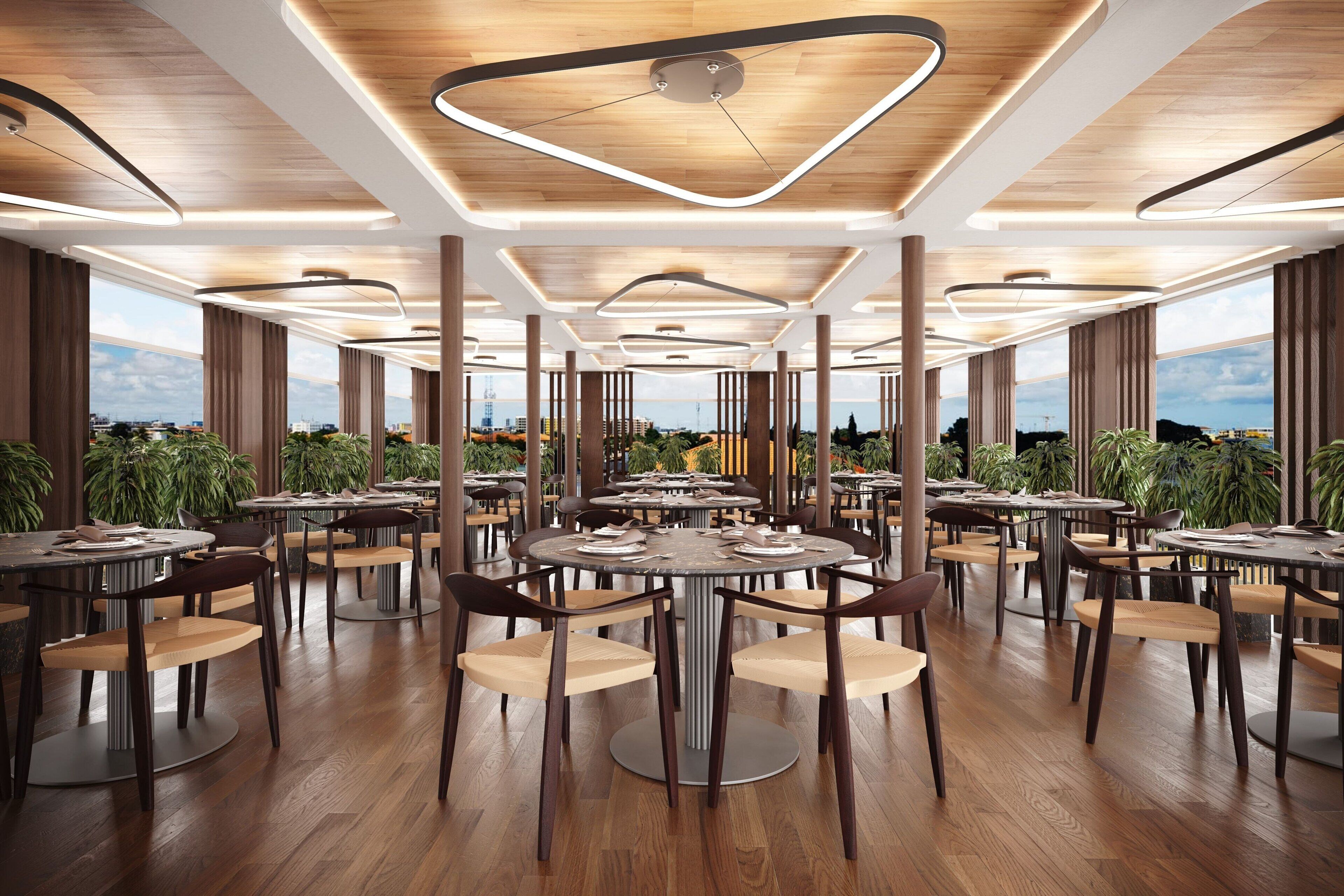 Een ruime eethoek met ronde tafels en stoelen, grote ramen met uitzicht op de stad en een modern plafondontwerp.
