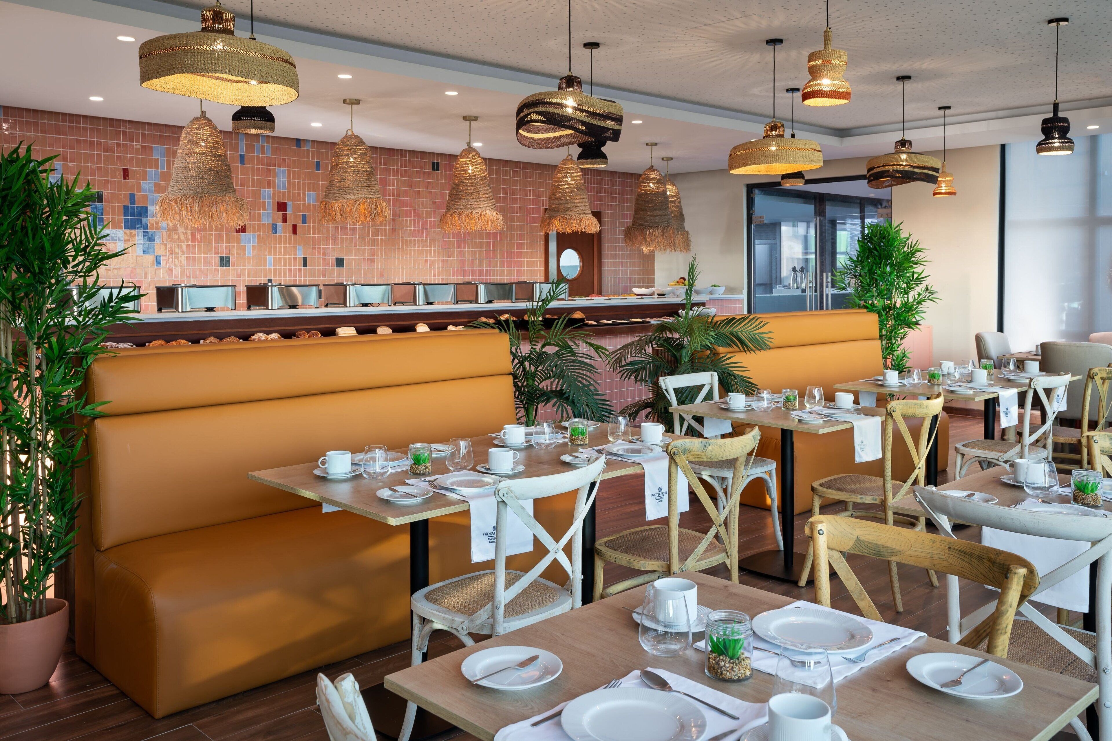 A restaurant with wooden tables and chairs, a buffet area, and hanging wicker lamps.