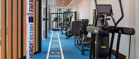 A gym with exercise equipment, a blue running track, and motivational posters on the walls.