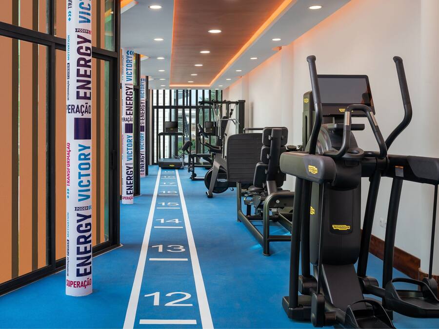 A gym with exercise equipment, a blue running track, and motivational posters on the walls.
