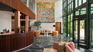 A spacious lobby with a high ceiling, a large abstract painting, and a seating area with a sofa and ottomans. - Protea Hotel Luanda (Luanda)