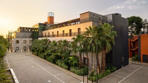 A modern hotel with a rooftop terrace, a parking area, and lush greenery. - Protea Hotel Luanda (Luanda)