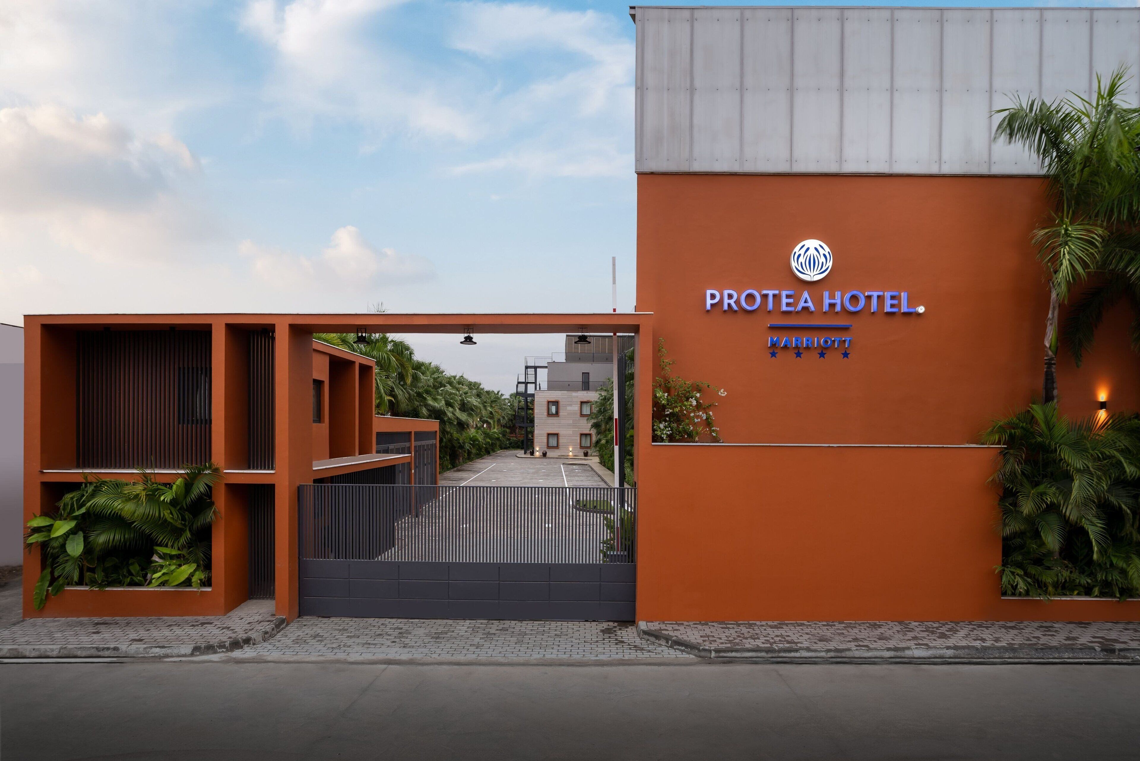 A hotel entrance with a modern design, featuring a prominent orange facade and a gated driveway.