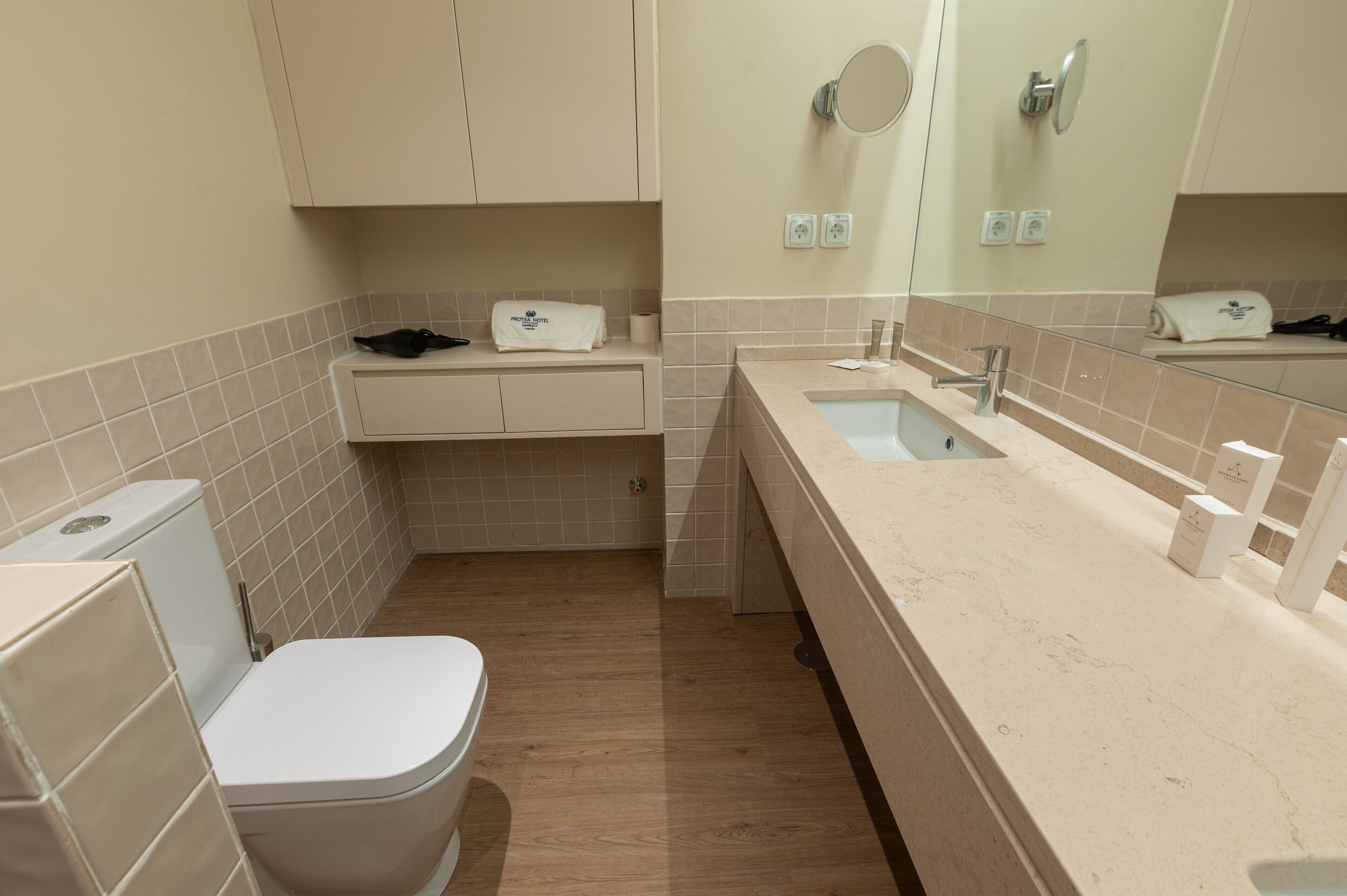 A compact bathroom with a toilet, sink, and mirror.