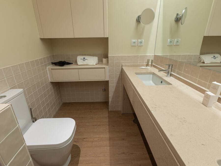A compact bathroom with a toilet, sink, and mirror.