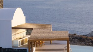 A modern outdoor dining area with a pergola, a pool, and a view of the sea. - Scenic Pool Villa with Sunset & Sea View by Santo Collection, The Villas (Santorini)