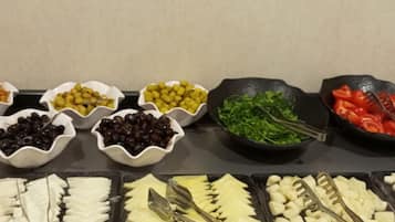 Een buffet met verschillende soorten eten, zoals olijven, kaas en groenten.