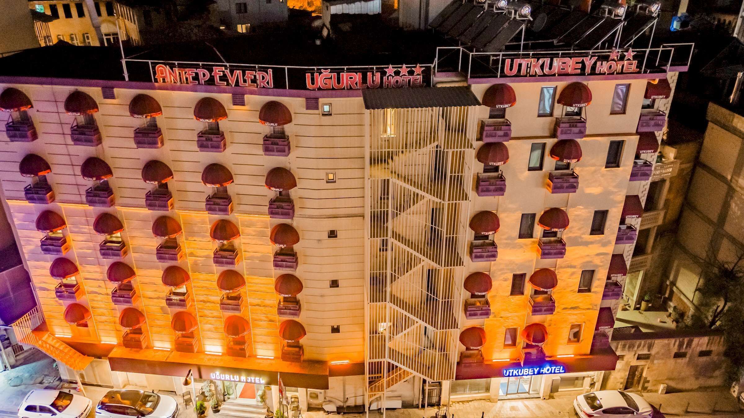 A hotel with multiple balconies, a central staircase, and a sign reading 'UTKUBEY HOTEL'.