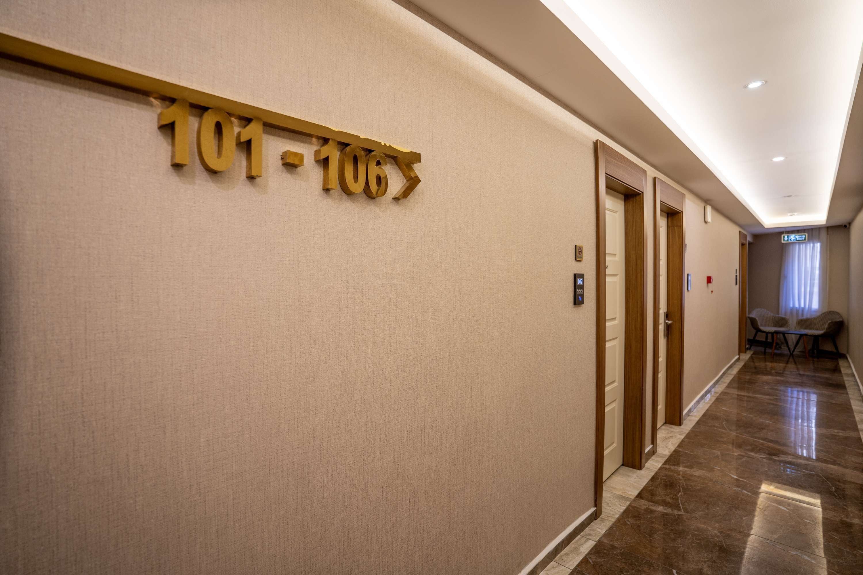 Ein Hotelkorridor mit einem Schild, das die Zimmernummern 101 bis 106 anzeigt.