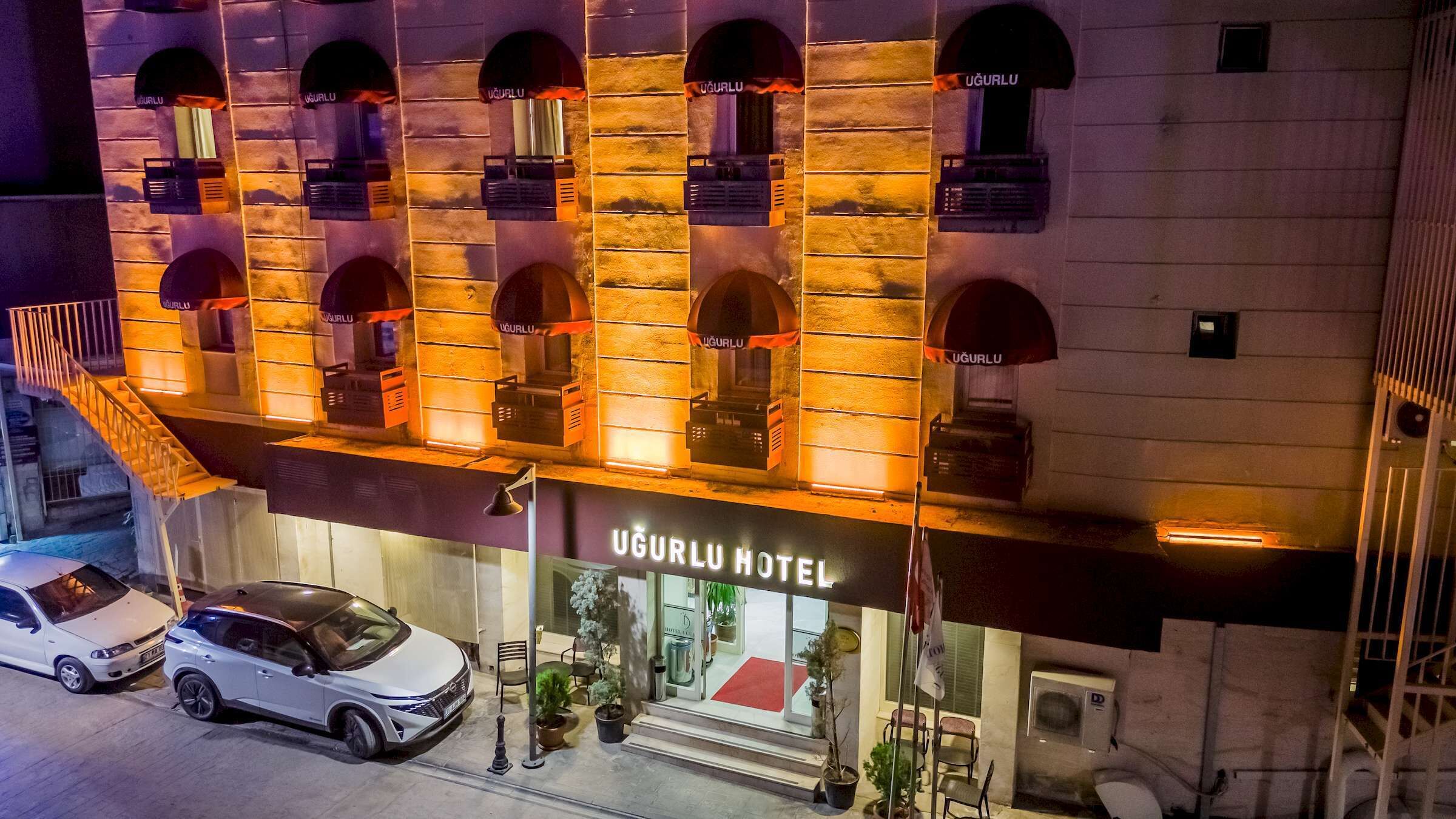 A hotel with multiple arched windows and a sign reading 'UGURLU HOTEL'.