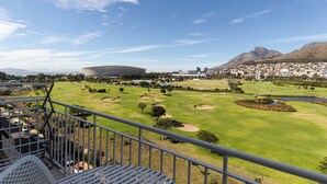 A golf course with a stadium and residential area in the background.