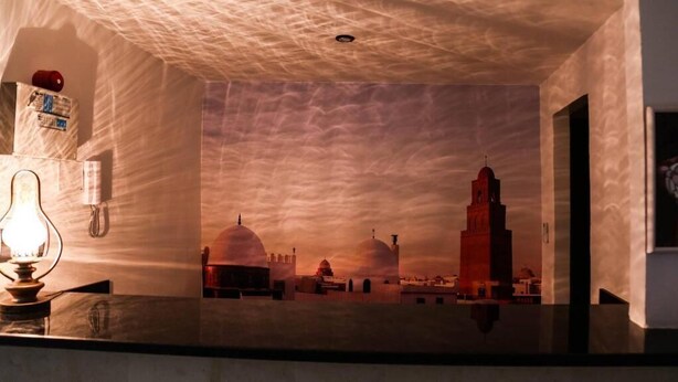 A room with a view of a cityscape at sunset, featuring domed buildings and a prominent tower. - Hôtel Métropole Résidence  (Tunis)