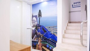 A reception area with a staircase leading to a balcony with a view of a coastal town and a palm tree. - Hôtel Métropole Résidence  (Tunis)
