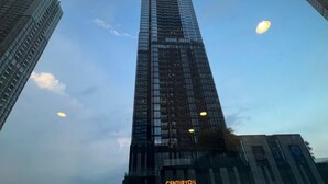 A tall, modern skyscraper with a glass facade, surrounded by other buildings.