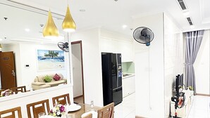 A modern kitchen with white cabinets, a black refrigerator, and a dining area with wooden chairs and a glass table set for four.