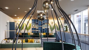 Un espace de détente moderne avec des sièges aux lignes courbes, une table centrale et un luminaire au plafond au design original.