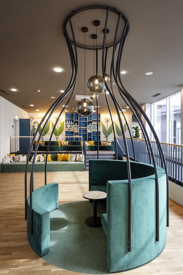 A modern lounge area with curved seating, a central table, and a unique ceiling light fixture.