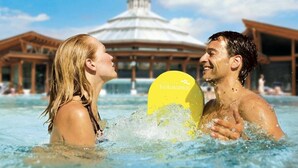Un couple dans une piscine, avec un flotteur jaune sur lequel on peut lire « Bad Radkersburg ».