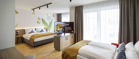 Una habitación de hotel moderna con una cama, un escritorio, un televisor y un ventanal amplio.
