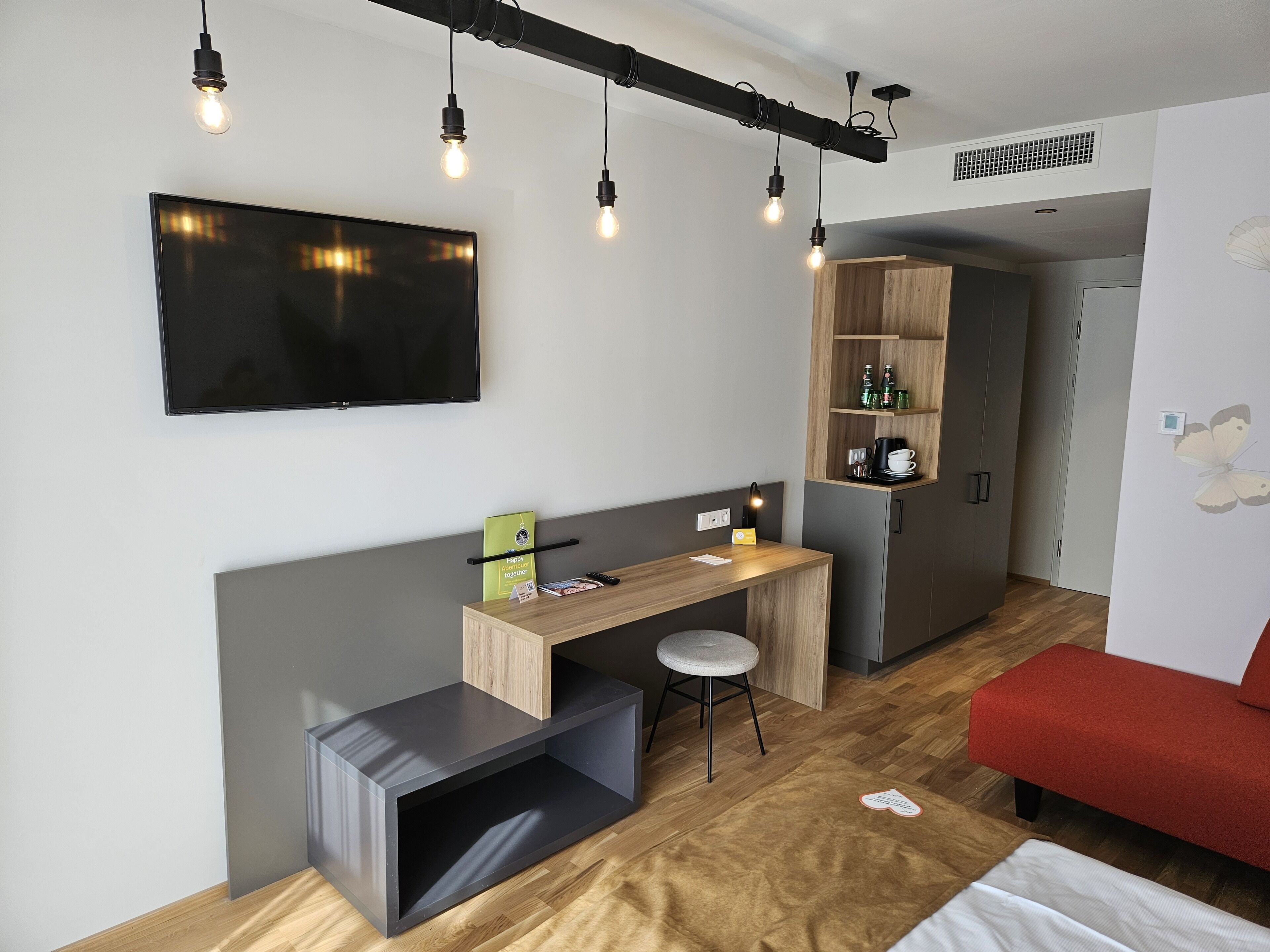 A modern room with a desk, chair, and a TV mounted on the wall.