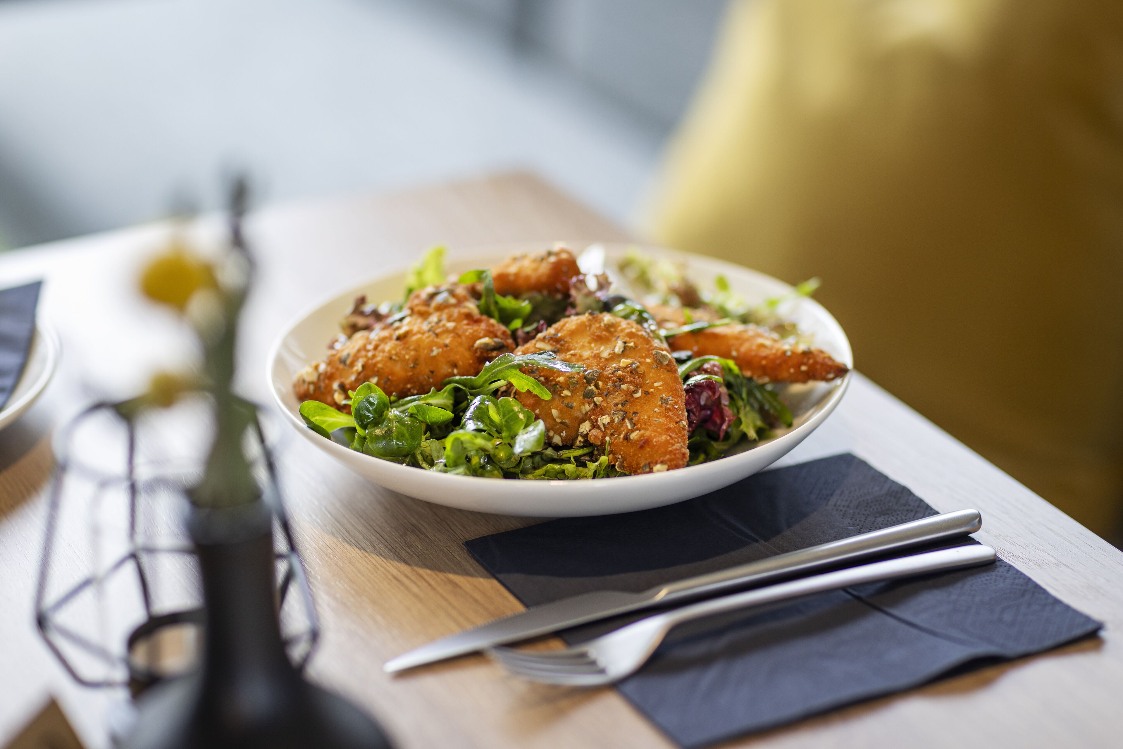 A bowl of food on a table with a napkin and cutlery.