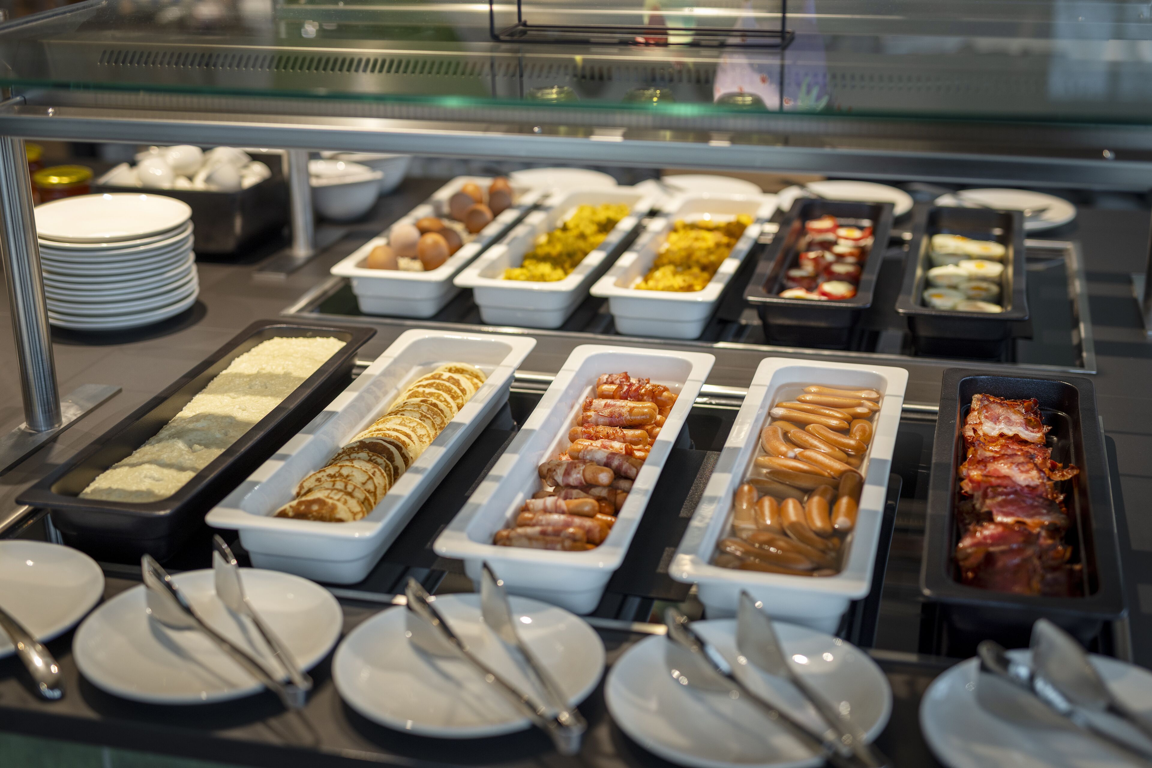 Un bufé con diversas opciones de comida, incluyendo carnes, quesos y productos de pastelería.