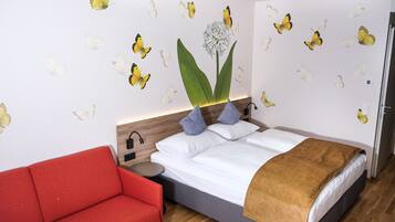 Un dormitorio con una cama, un sofá rojo y adornos de mariposas en la pared.