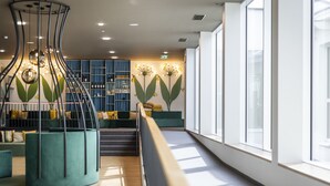 Un intérieur moderne agrémenté d’un escalier en colimaçon, de coins salon et d’une grande fenêtre laissant entrer la lumière naturelle.
