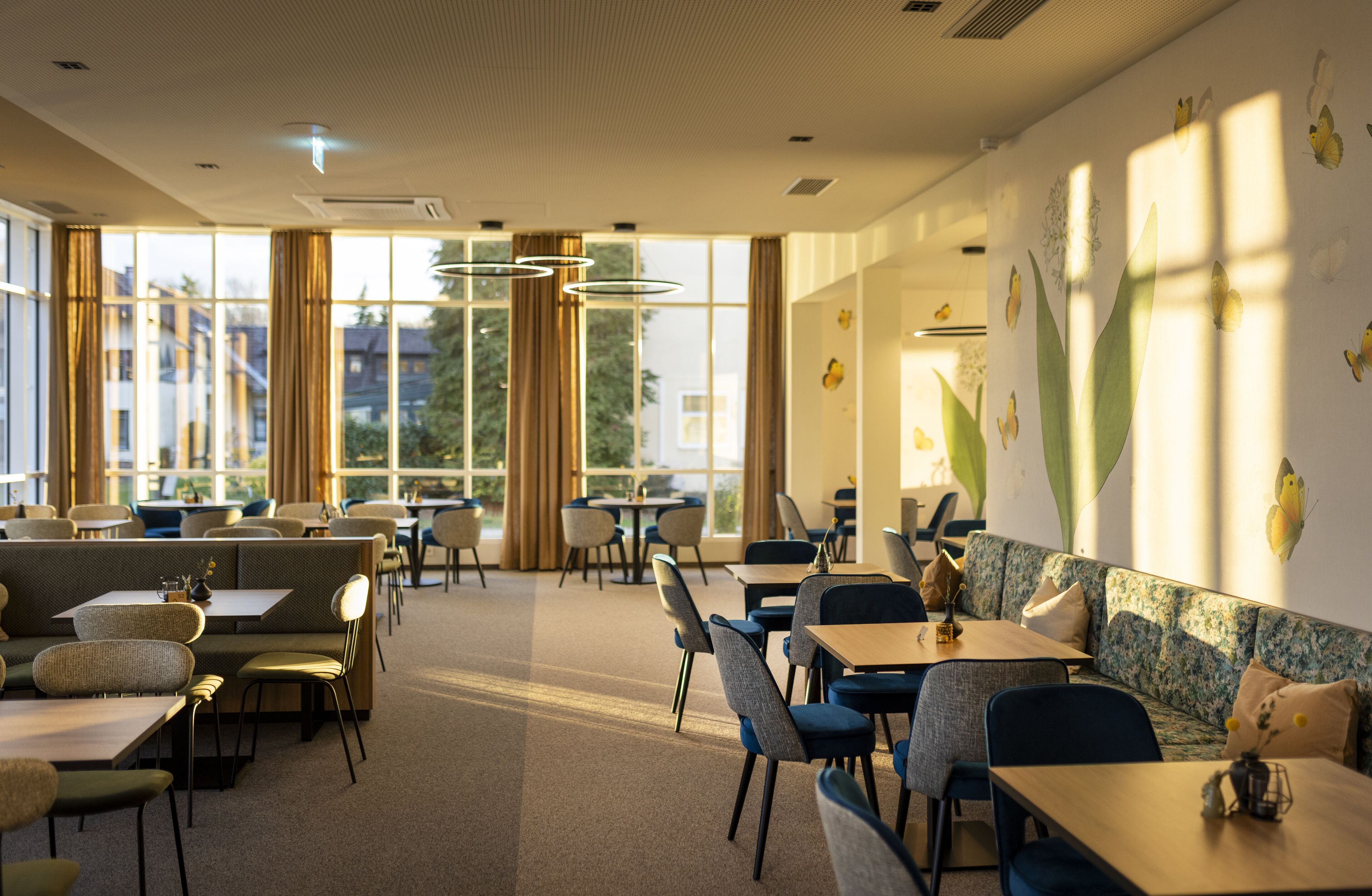 A modern dining area with booths and tables, large windows, and decorative wall art.