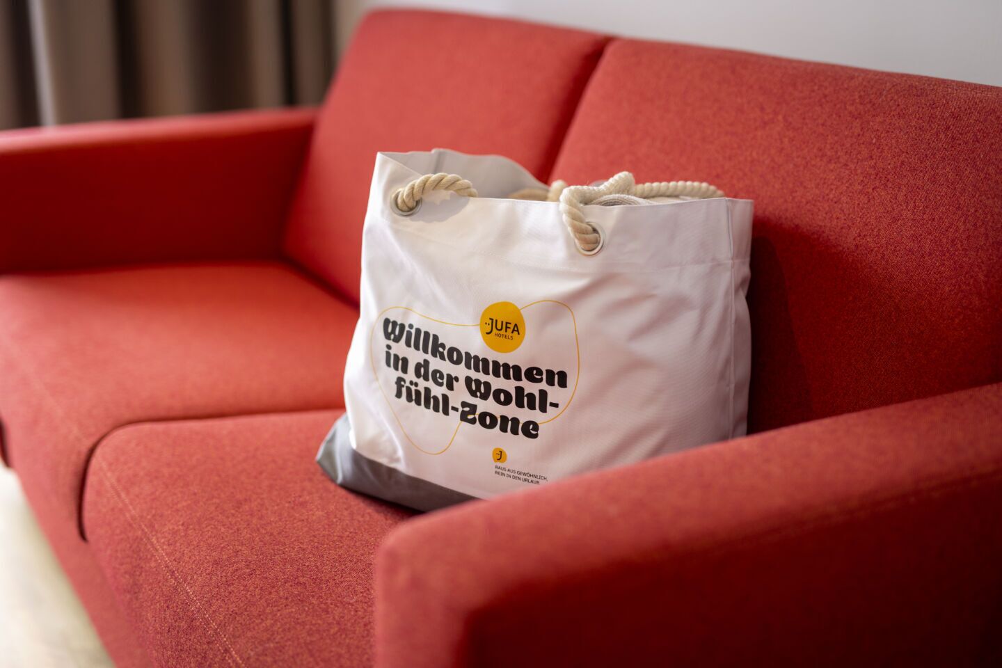 A white tote bag with text on a red couch.
