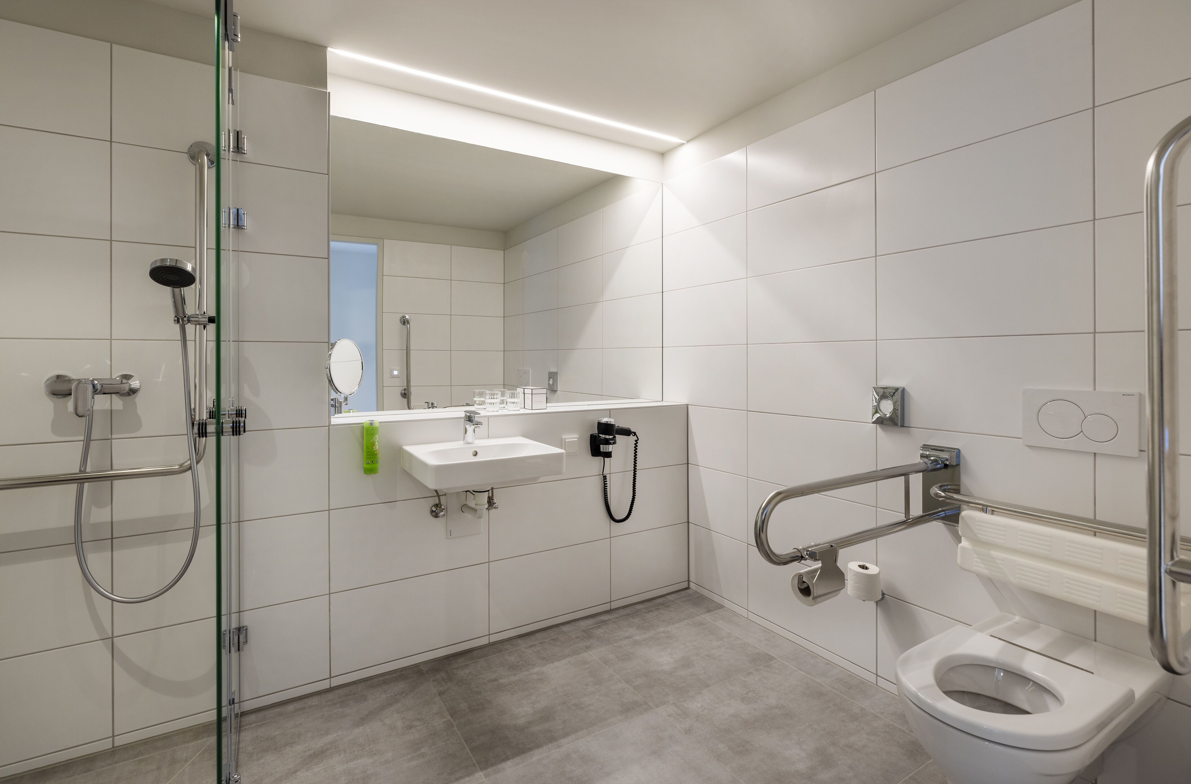 Ein modernes Badezimmer mit Duschkabine aus Glas, einem weißen Waschbecken und einer Toilette.