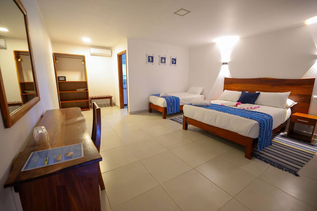 A hotel room with a wooden bed, a desk, a mirror, and a wardrobe.