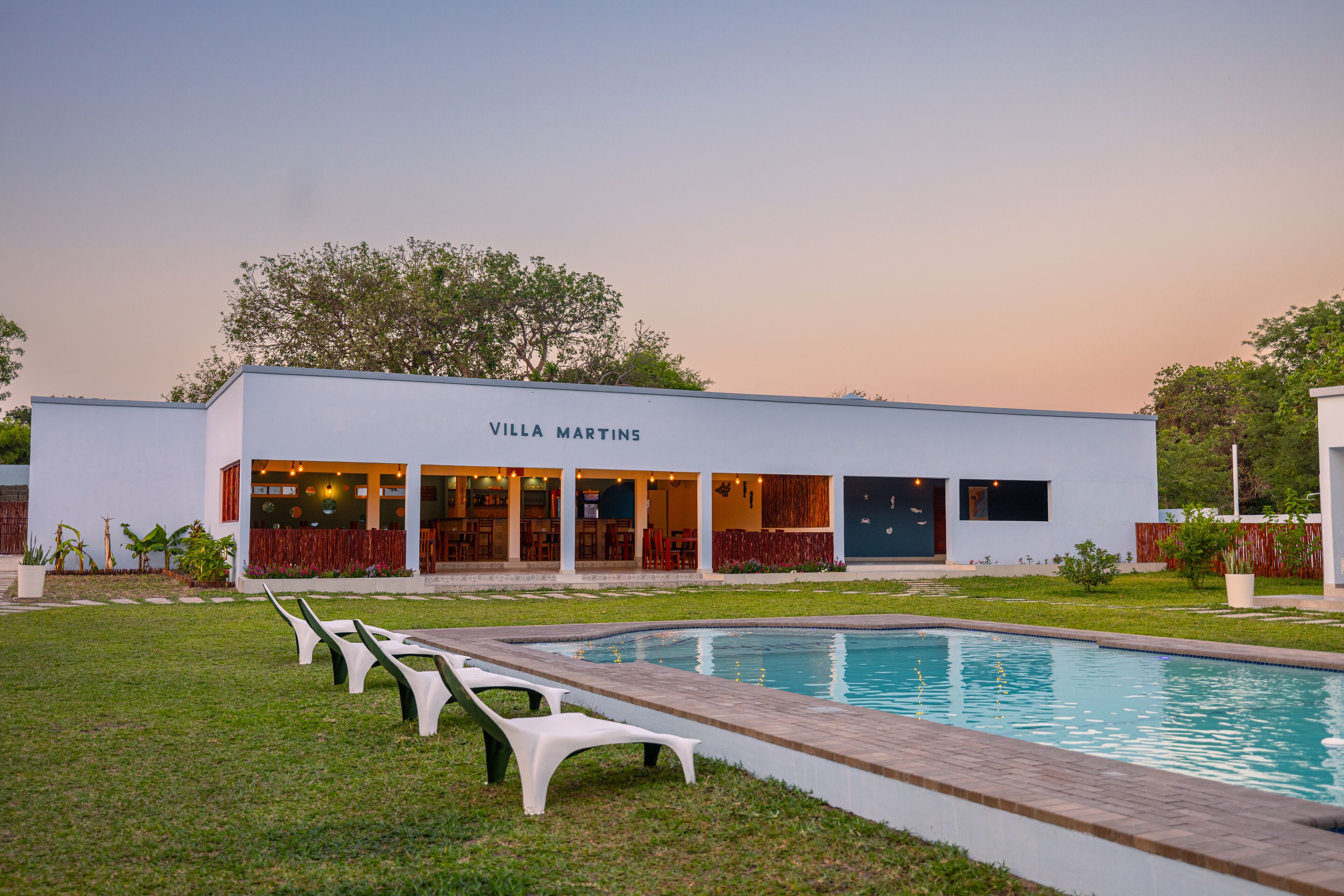A modern villa named Villa Martins with a swimming pool, outdoor seating, and a well-maintained lawn.