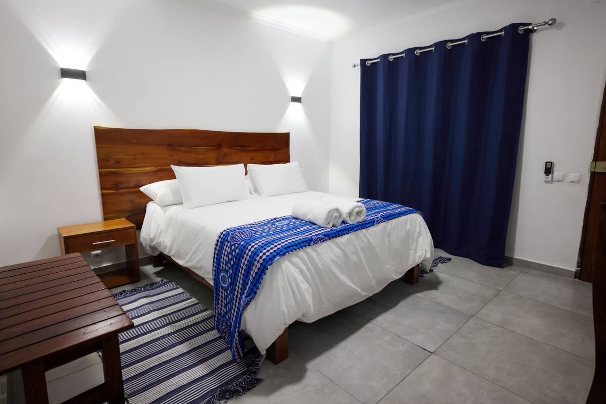 A neatly made bed with a blue and white patterned blanket, a wooden headboard, and two bedside lamps.