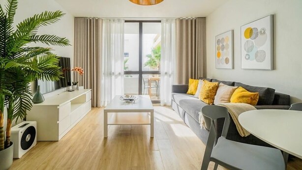 Ein modernes Wohnzimmer mit einer Couch, einem Couchtisch und einer Zimmerpflanze.