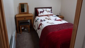 Una camera da letto con un letto, un comodino, una cassettiera e uno specchio.