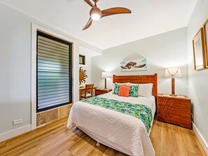 A bedroom with a bed, wooden headboard, bedside tables, a ceiling fan, and a window with blinds. - 3 Bedroom Deluxe Oceanfront with A/C - Poipu Shores 302B (Koloa)