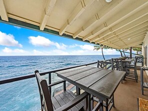 An outdoor dining area with tables and chairs, overlooking the ocean. - 3 Bedroom Deluxe Oceanfront with A/C - Poipu Shores 302B (Koloa)