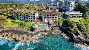 A resort with multiple buildings, a swimming pool, and a rocky coastline.