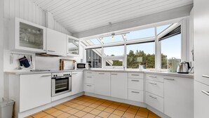 A modern kitchen with white cabinetry, a built-in oven, a microwave, and a large window providing natural light. - "Josef" - 950m from the sea by Interhome (Fanø)
