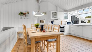A modern kitchen with white cabinets, a wooden dining table, and a tiled floor. - "Josef" - 950m from the sea by Interhome (Fanø)