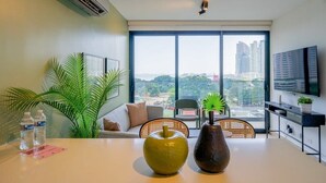 A modern living room with a large window, a flat-screen TV, and a dining area with a table and chairs. - w* | Polished 1BR in San Francisco w/ Balcony View (Panamá)