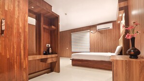 A modern bedroom with a wooden wardrobe, a bed, a bedside table, and a vase of flowers. - SANJEEVINI AYURVEDA AND YOGA RETREAT (Aluva)