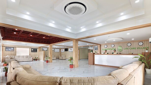 A spacious lobby with a reception desk, seating area, and framed artwork on the walls. - SANJEEVINI AYURVEDA AND YOGA RETREAT (Aluva)