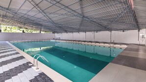 An indoor swimming pool with a tiled floor and a metal roof structure. - SANJEEVINI AYURVEDA AND YOGA RETREAT (Aluva)