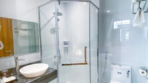 A modern bathroom with a glass-enclosed shower, a white sink, and a toilet. - An Hotel Ha Long (Bai Chay)
