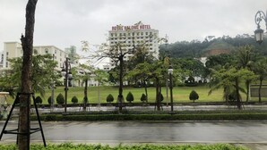 A Royal Halong Hotel with a view of a landscaped park and a road in the foreground. - An Hotel Ha Long (Bai Chay)