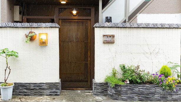 A traditional Japanese entrance with a wooden door, a small lantern, and potted plants. - Hotel Belle Via Tokyo (Tokyo)