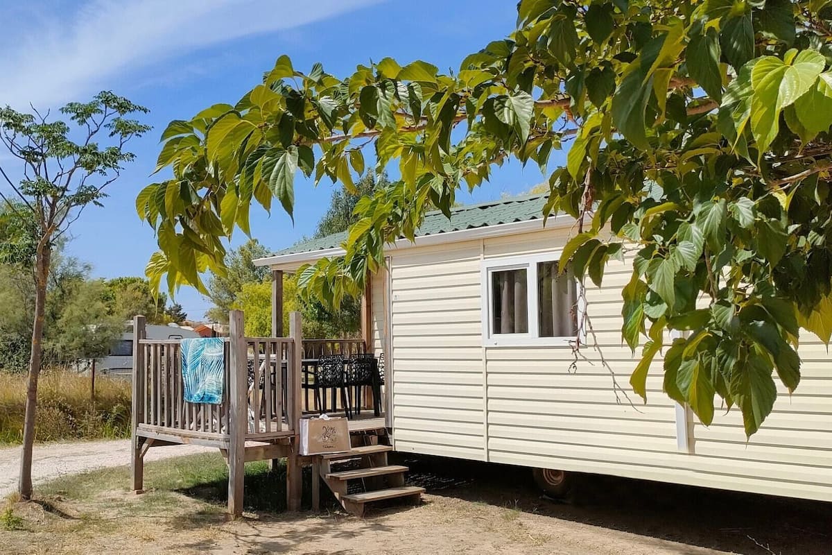 A mobile home with a wooden deck and a covered porch.