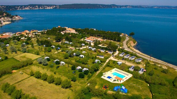 An aerial view of a coastal area with multiple houses, a swimming pool, and a playground. - Camping Felix de la Bastide (Saint-Mitre-les-Remparts)